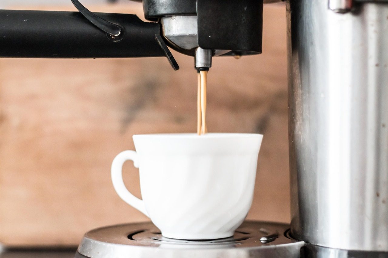 Machine à café versant un expresso dans une tasse blanche