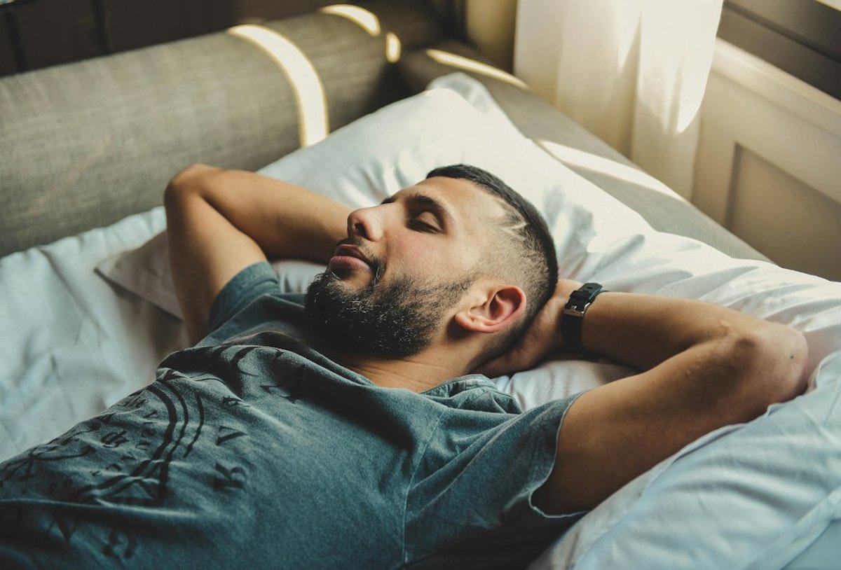 homme s'étirant au réveil dans son lit