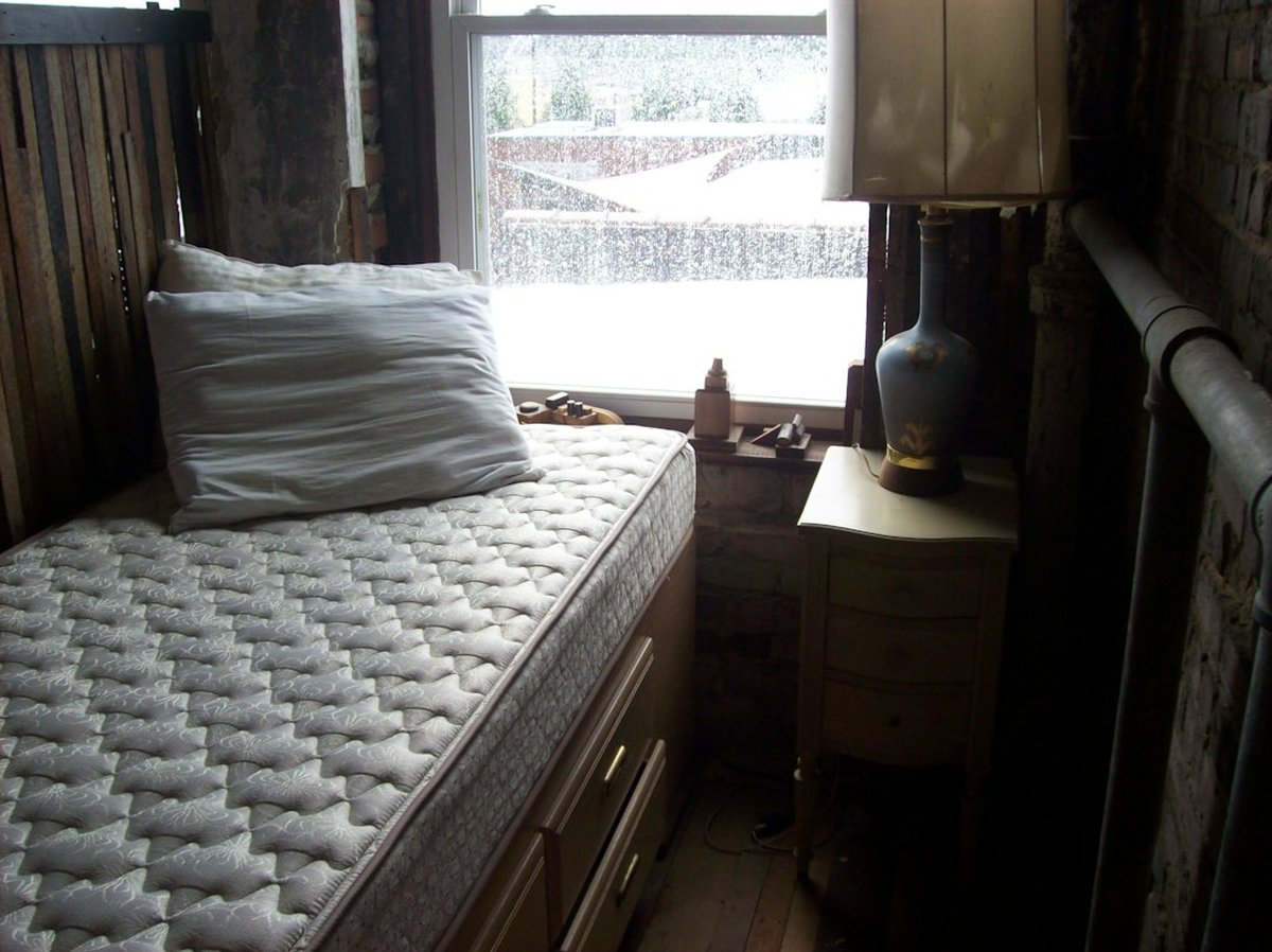 matelas sur cadre de lit en bois près d'une fenêtre