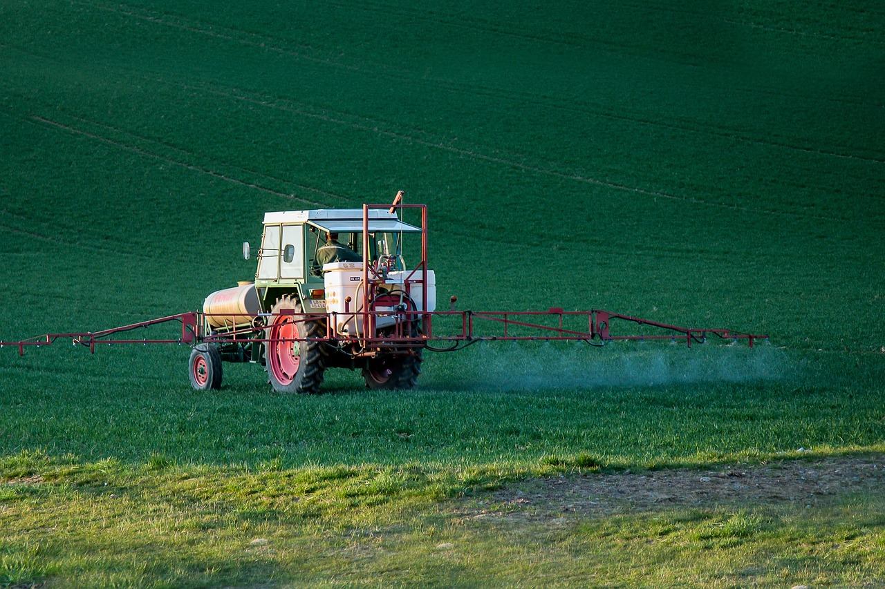 tracteur pulvérisant un champ avec nuage visible