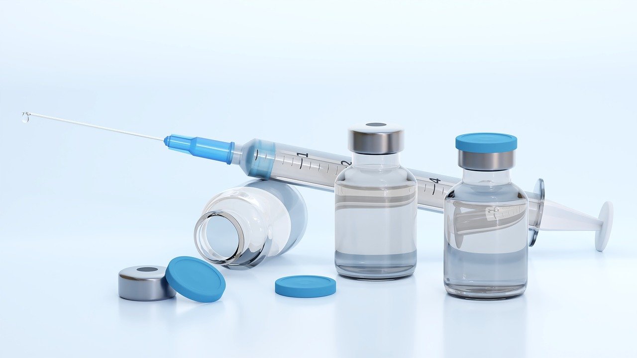 seringue et flacons de vaccin sur fond bleu
